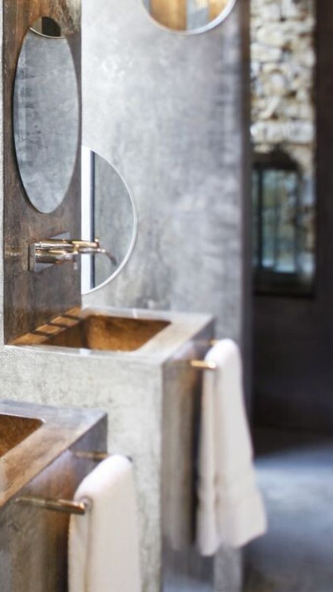 Modern bathroom featuring a sleek concrete sink with a circular mirror above. Soft towels are neatly hung beside the sink, creating a clean and stylish ambiance.
