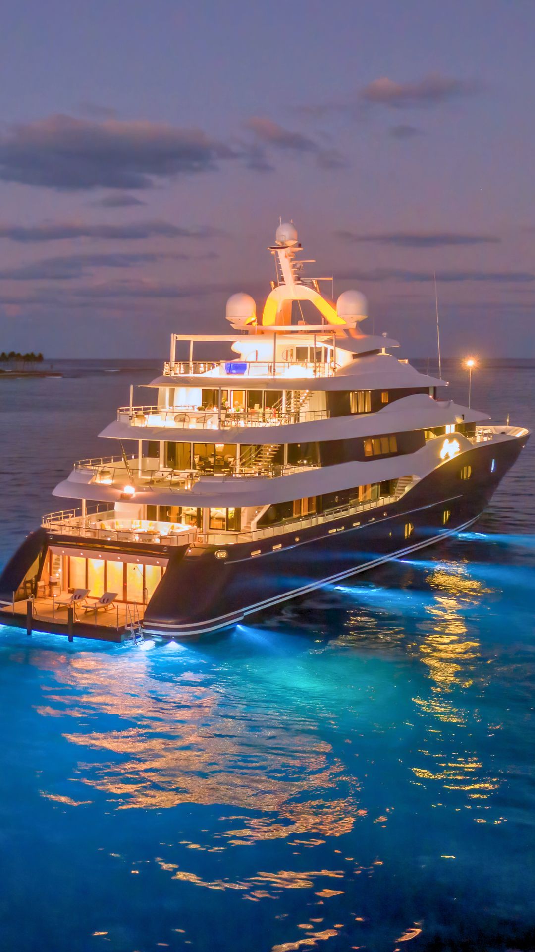 A luxurious yacht illuminated at night, floating on calm waters with a glowing hull and soft lights. The backdrop features a scenic twilight sky with some clouds.