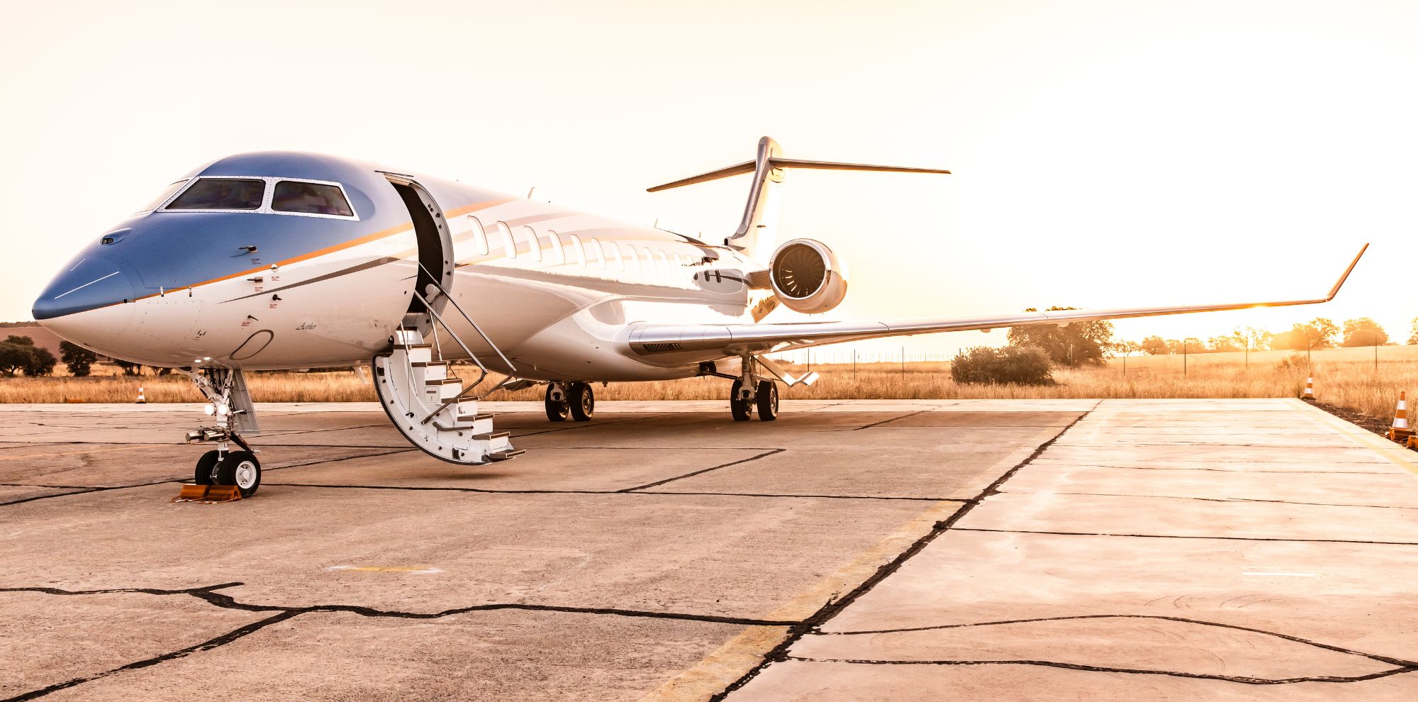 A sleek private jet parked on a runway at sunset, showcasing its elegant design and shiny exterior.