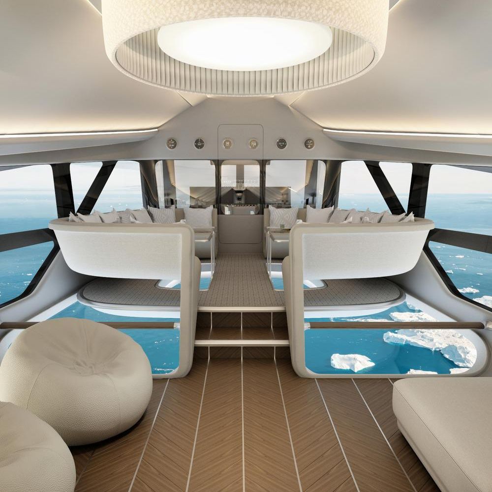 A sleek, modern interior of a luxury aircraft featuring large windows with ocean views. The space includes comfortable, minimalist seating, a central light fixture, and a wooden floor with soft lounge seating. The design reflects elegance and tranquility.