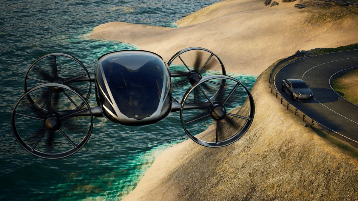 A futuristic drone with four propellers hovers above a coastal landscape, overlooking a winding road and a sleek car parked nearby, with sandy cliffs and turquoise waters in the background.