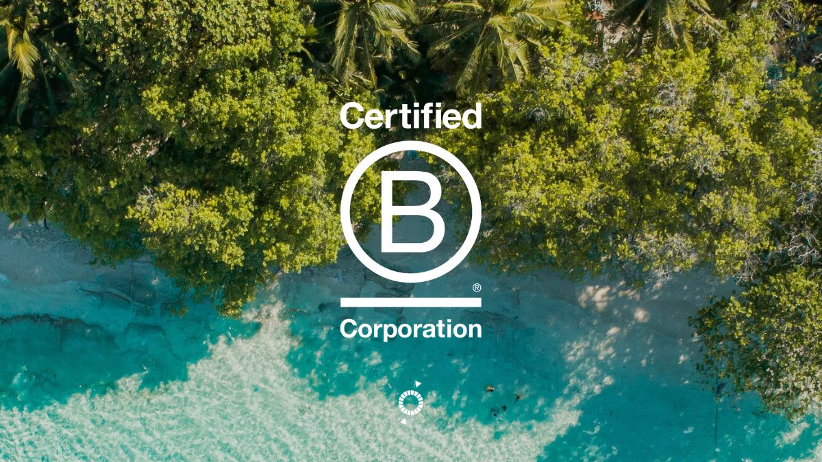 Aerial view of a beach with turquoise water and lush green trees, featuring the "Certified B Corporation" logo prominently in the center.