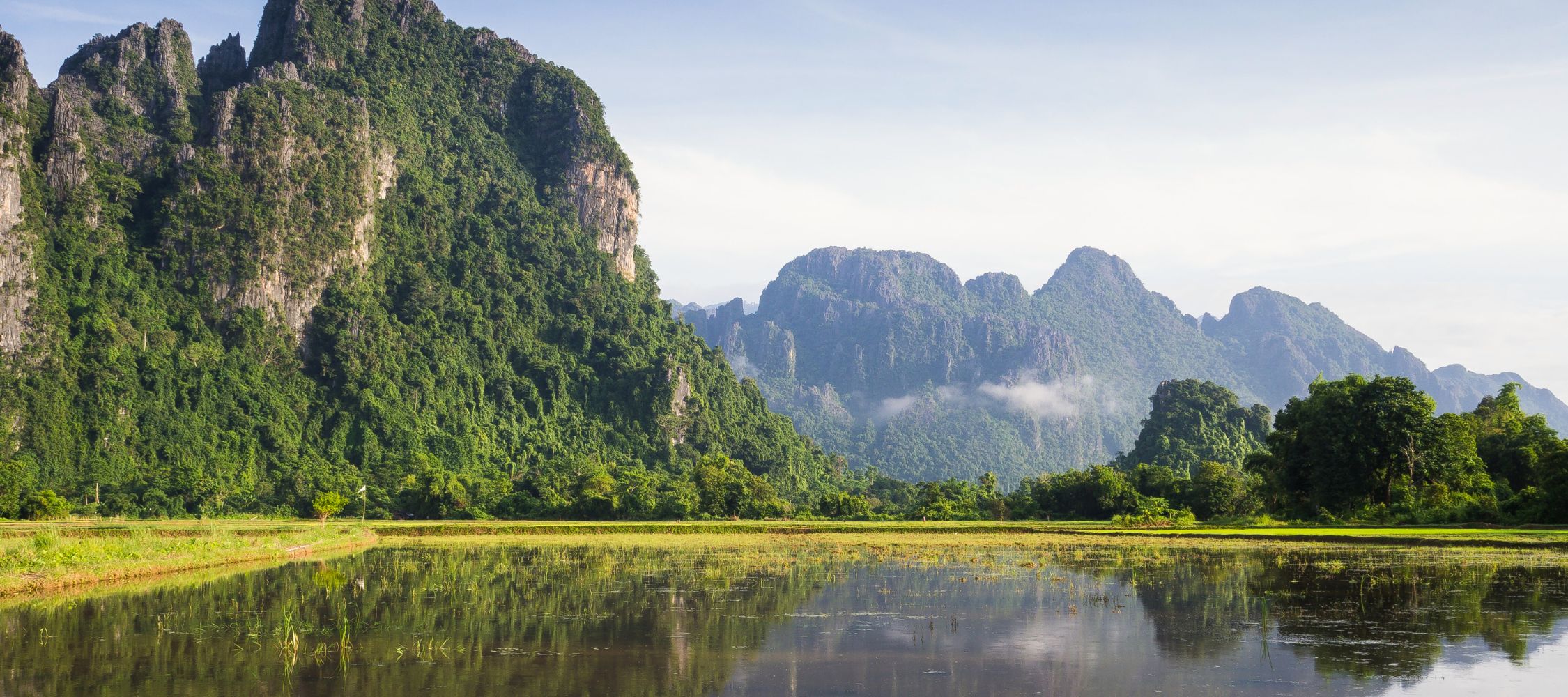Green Cambodian mountains towering over a mirror lake