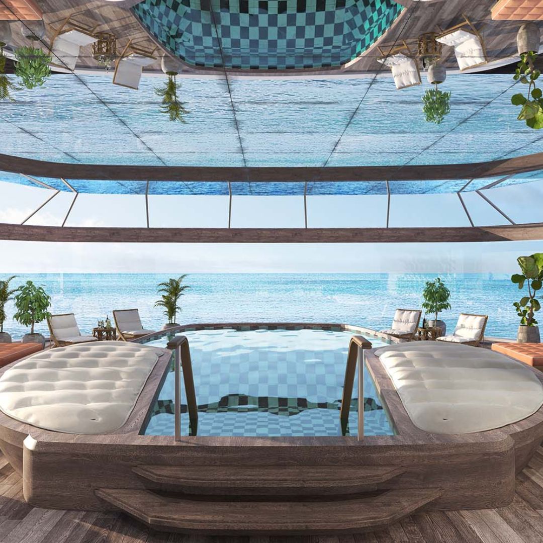 Luxurious indoor pool overlooking the ocean, featuring a glass ceiling and panoramic views. Plush seating surrounds the pool, with potted plants adding greenery to the serene space.
