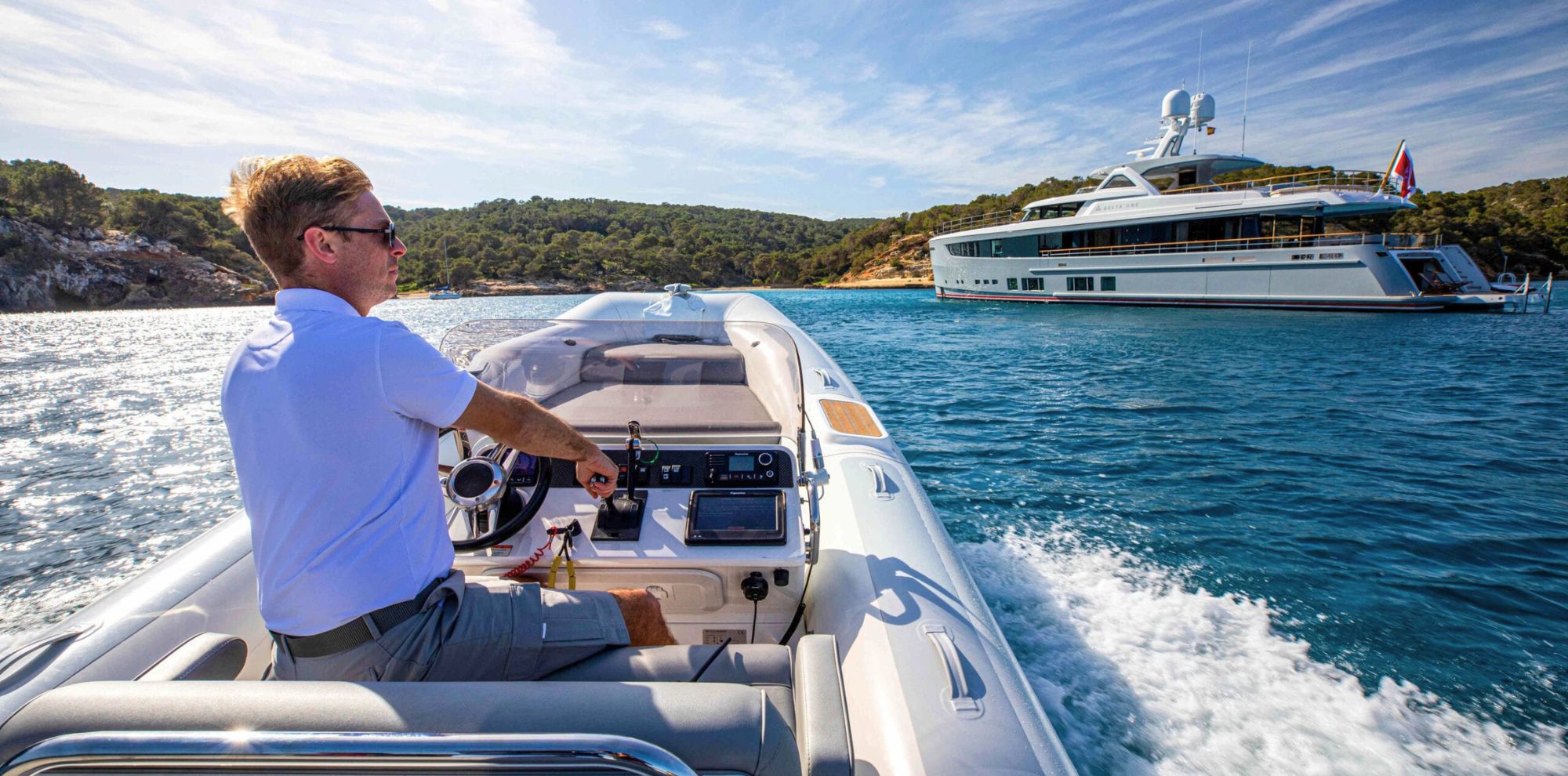Man in tender driving towards yacht