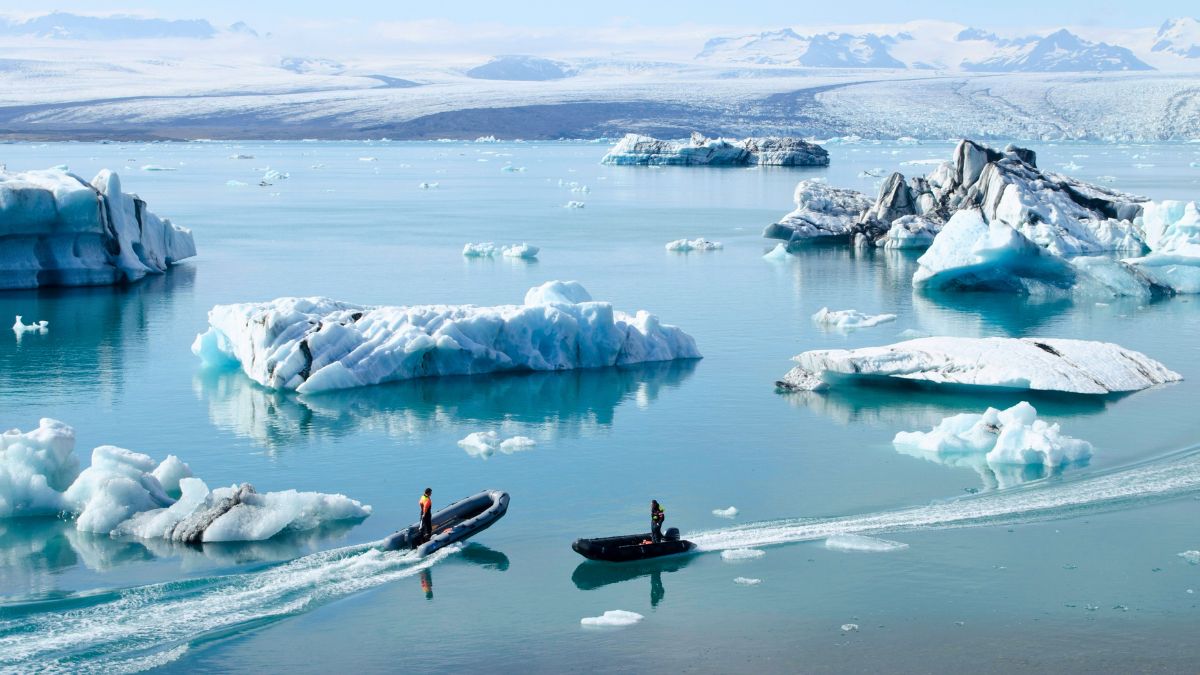 Two RIB boats in the waters of Iceland, driving around the ice blocks, ready for a luxury travel concierge experience with breathtaking views of a glacier