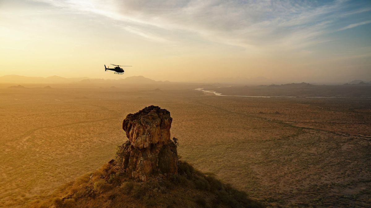 Private helicopter flying over Kenya at sunset for guests looking for luxury travel concierge services