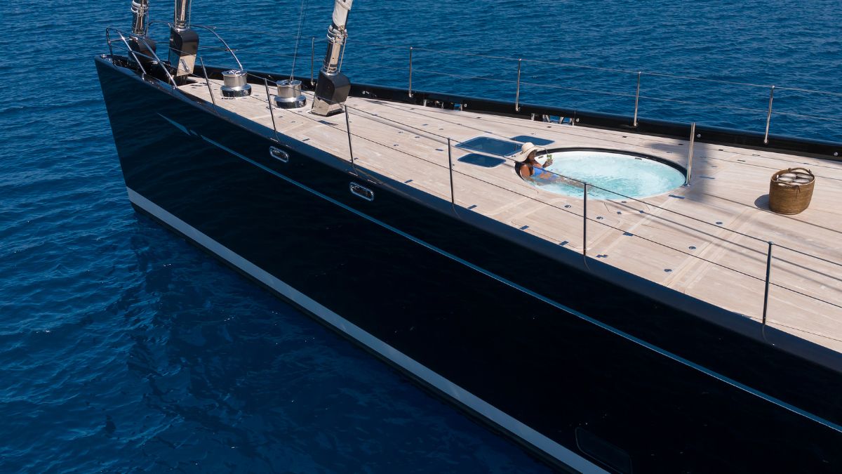 Foredeck of large luxury sailing boat in the blue sea with woman in Jacuzzi