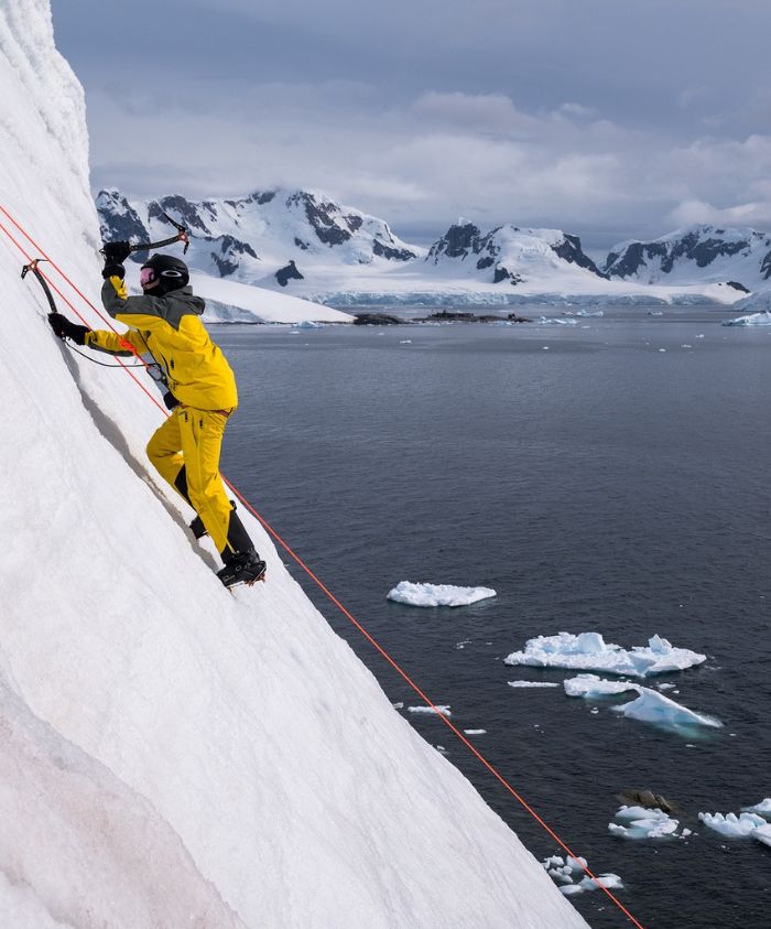 Man in a harness climbing an icy mountain in Antarctica