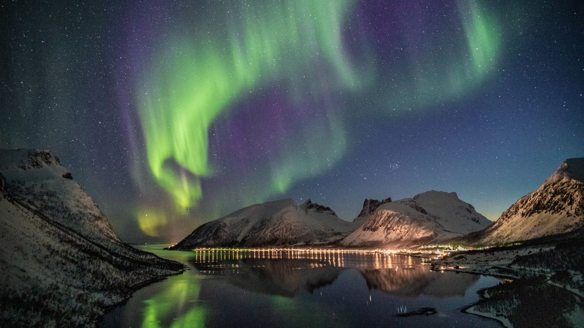 Views of the northern lights in Norway over the snow-capped mountains, as part of an itinerary for guests using our vip concierge services