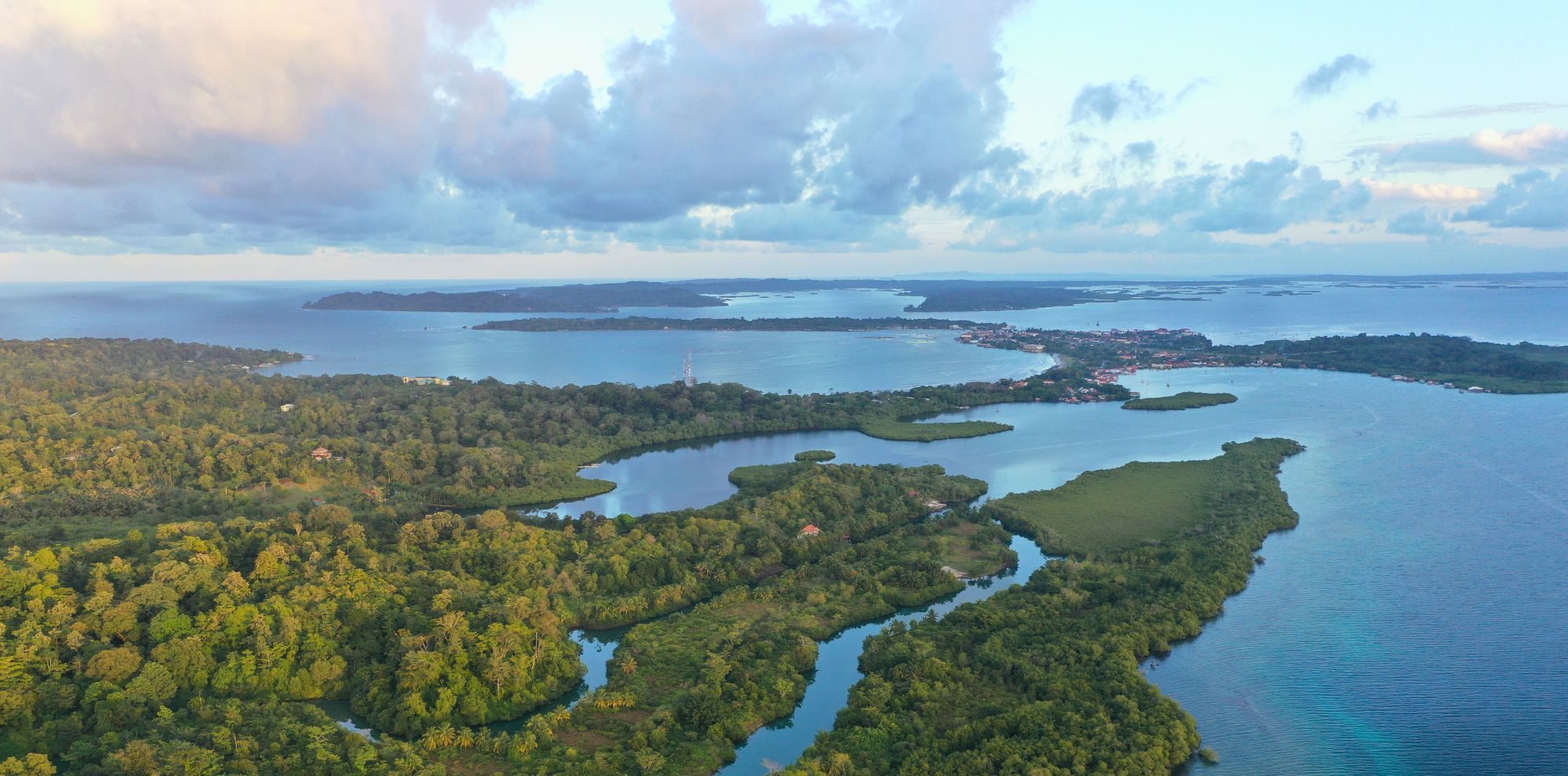 Aerial view of a sprawling tropical archipelago with lush green forests, winding waterways, and scattered coastal settlements.