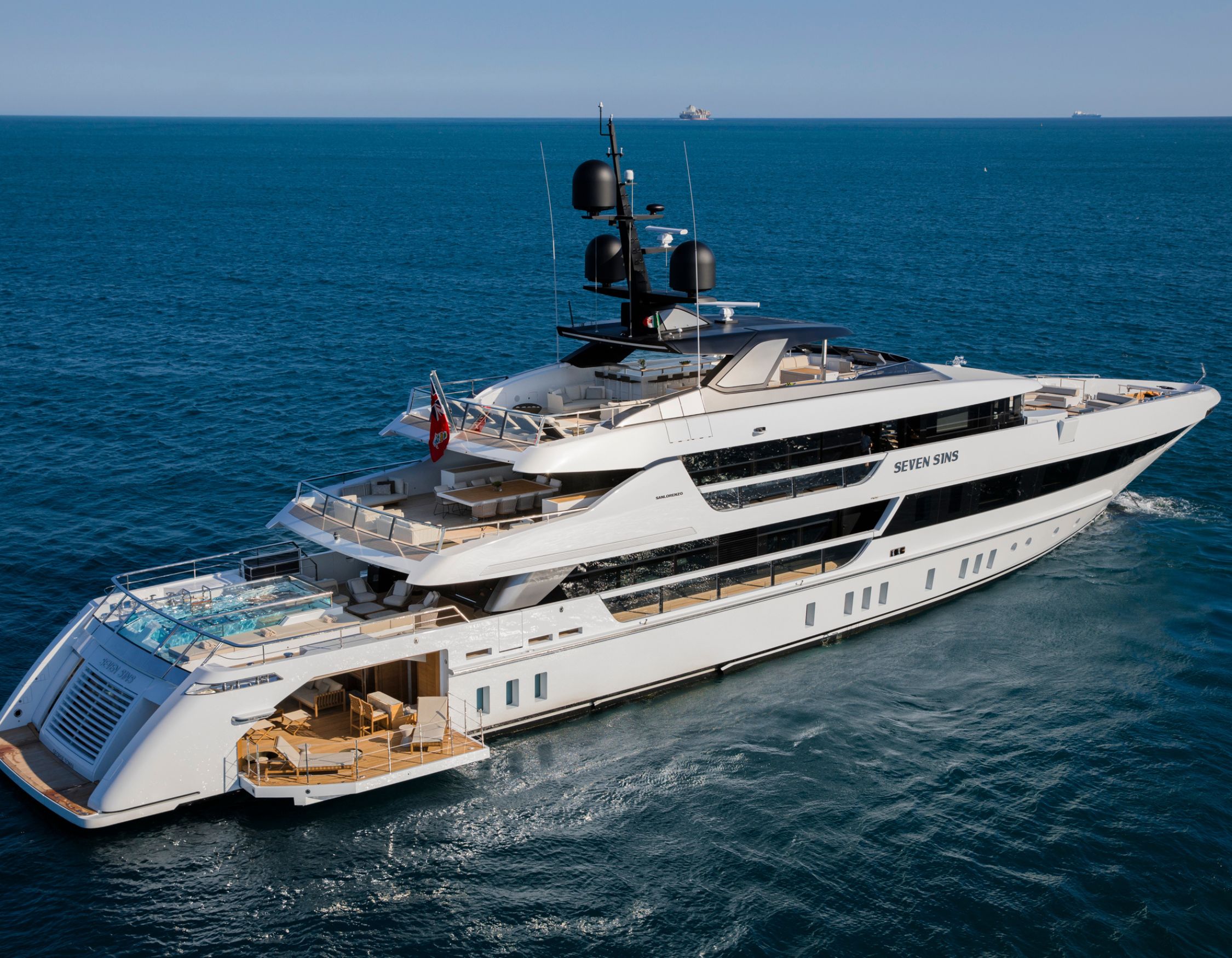 High-angle view of a luxury motor yacht SEVEN SINS with a glass-bottom pool on the deck and a fold-out beach club.