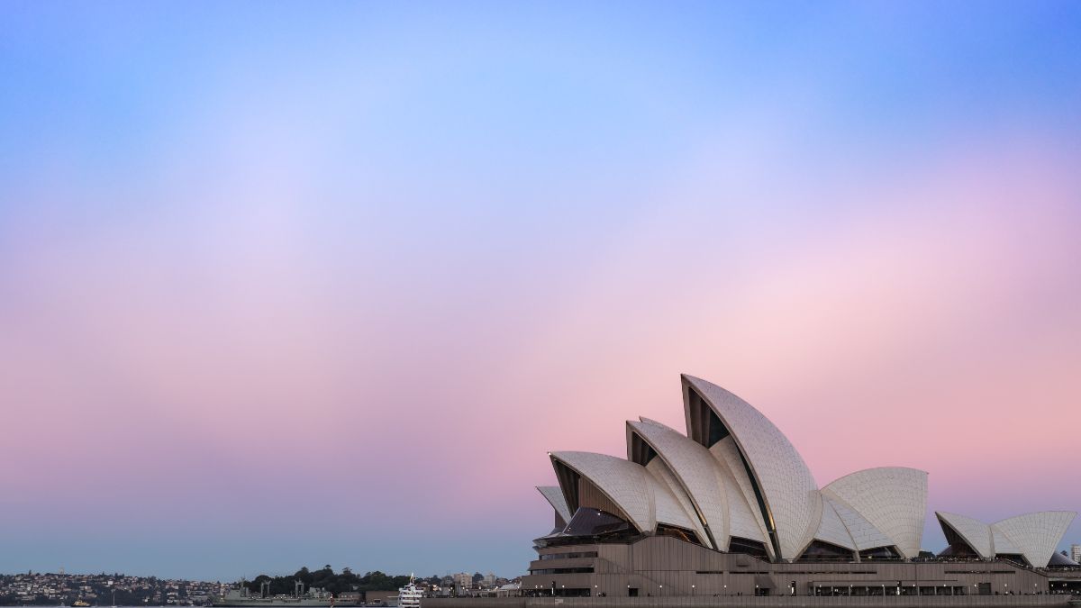 The Sydney Opera House silhouetted against a pastel pink and blue sky at dusk.