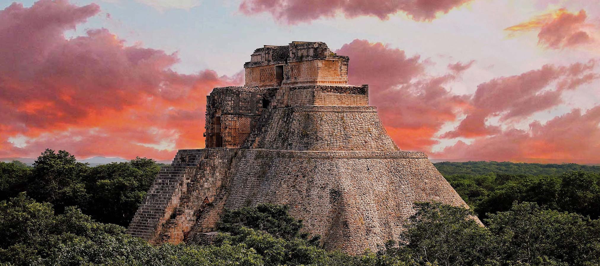 A large stone pyramid stands amid lush greenery, with a dramatic sunset sky in shades of orange and purple behind it.