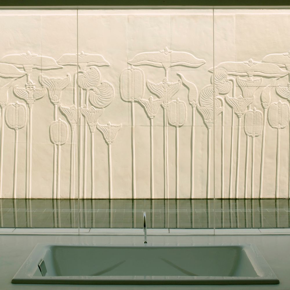A textured wall featuring embossed floral designs in soft white tones. A sleek, modern sink is positioned in the foreground, reflecting the minimalist aesthetic.