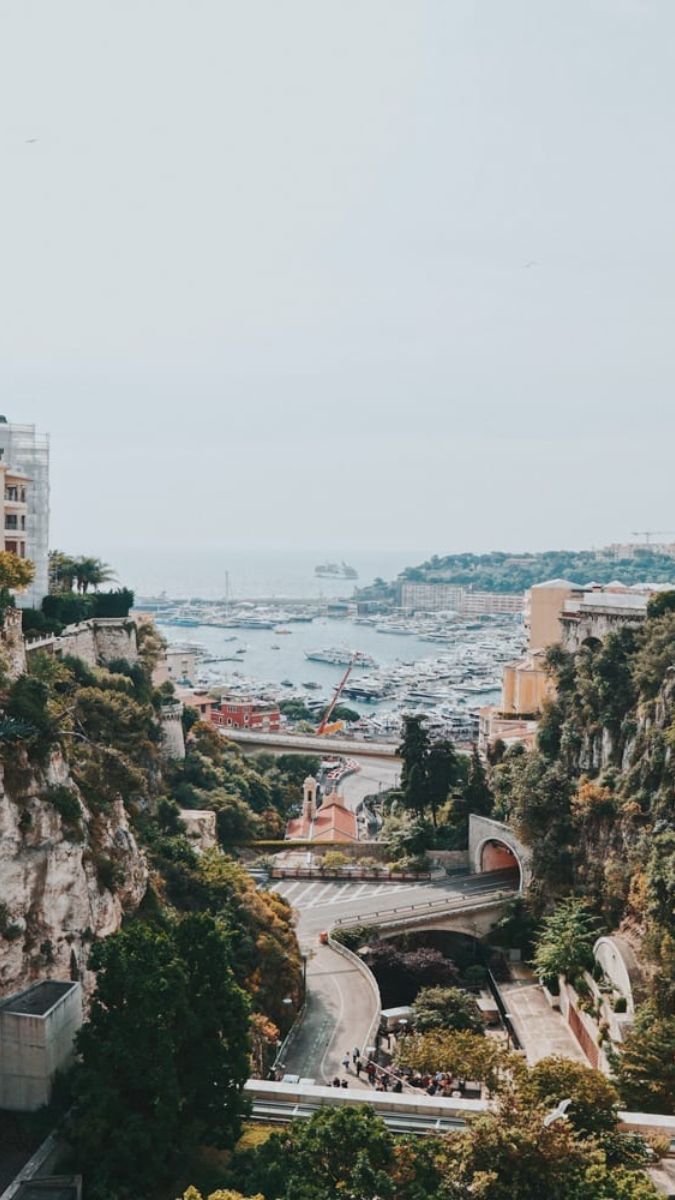 Yachts in a Monaco's Port Hercules, with coastal cliffs, a scenic highlight of a luxury South of France vacation.