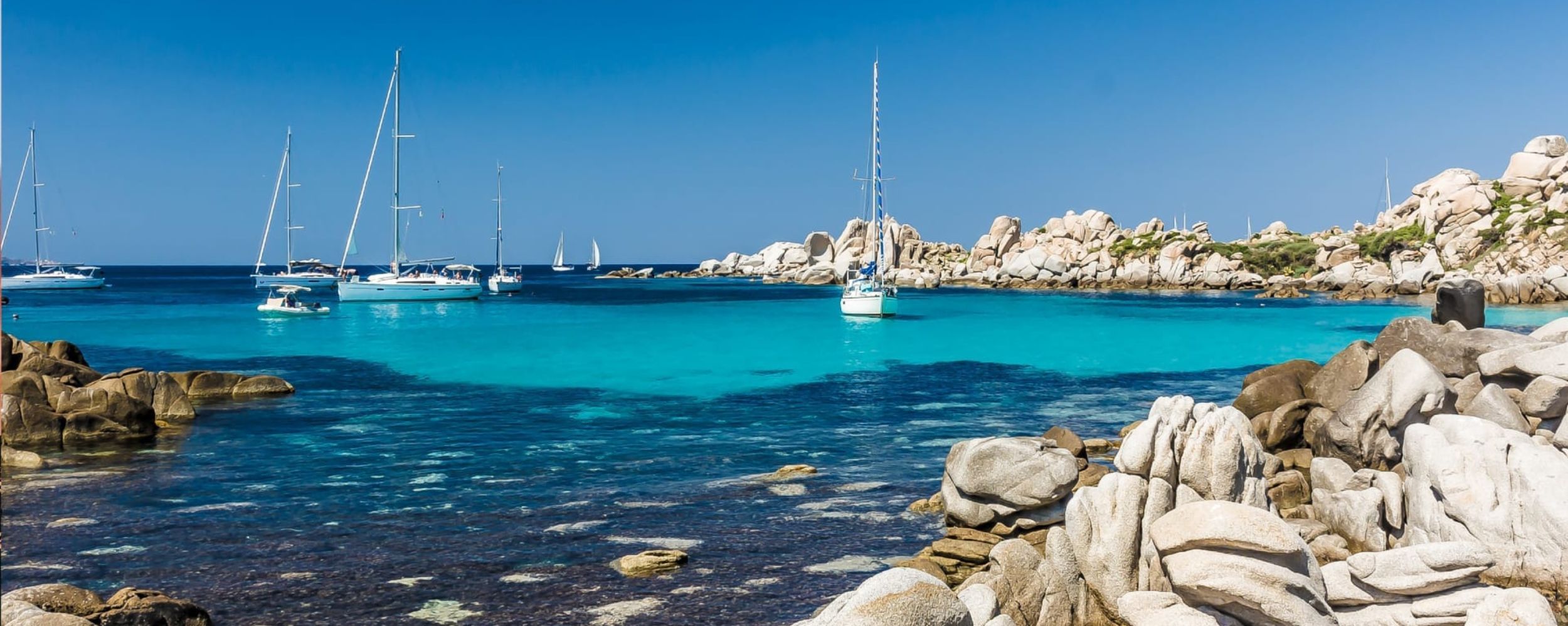 Sailing boats anchored in a turquoise coloured bay on a  luxury France vacation.