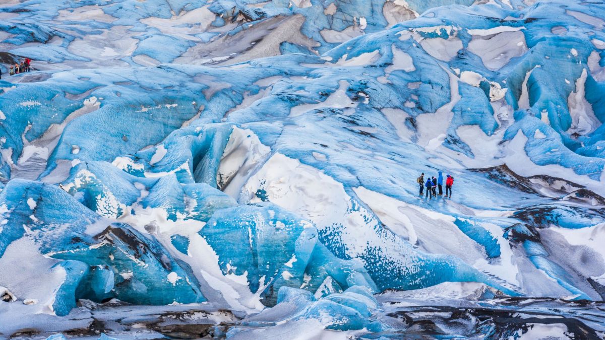 Adventurers trekking across a glacier, part of a personalized Iceland vacation itinerary for an epic Iceland family vacation.