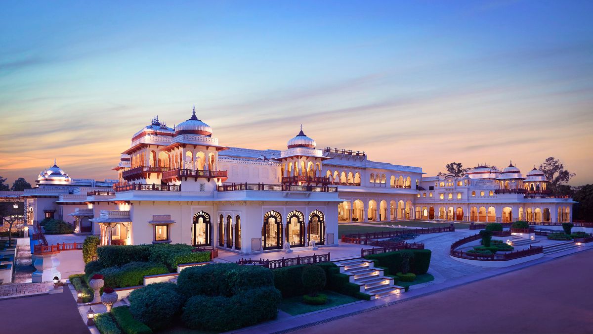 Grand illuminated heritage hotel, Rambagh Palace at sunset, considered one of the most expensive hotels in India for luxury stays.