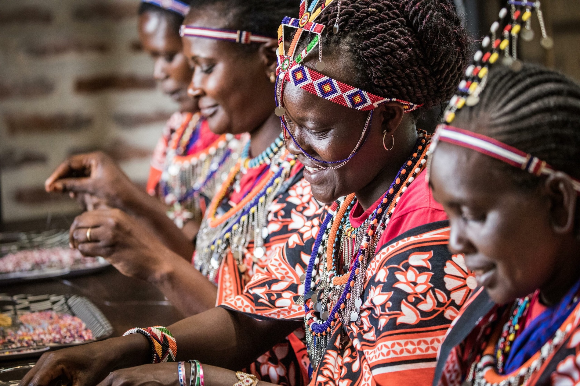 Women crafting beadwork in traditional Maasai attire in Kenya