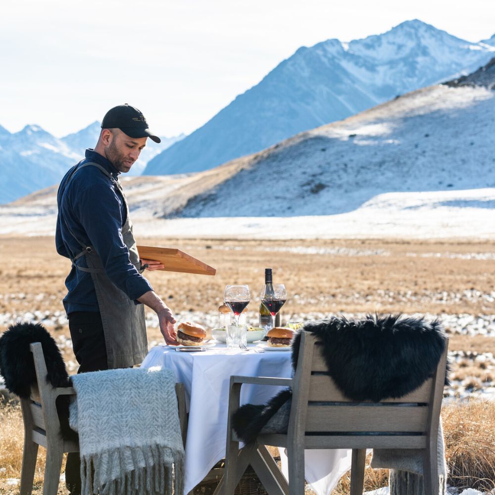 Waiter setting a table outside with burgers
