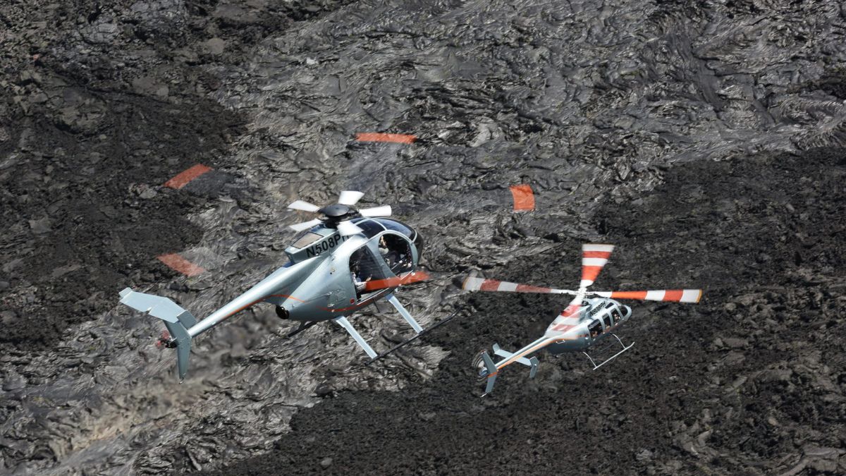 Two helicopters flying over the volcanic landscape in Hawaii on a luxury adventure holiday