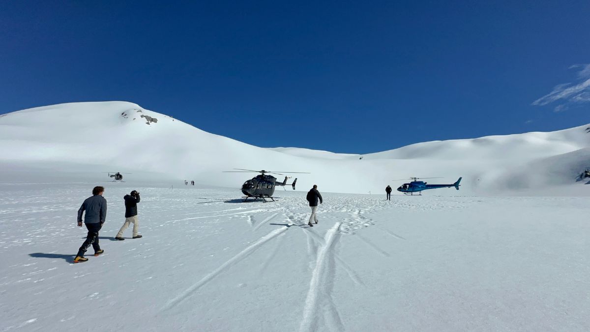 group walking towards helicopters landed on a glacier