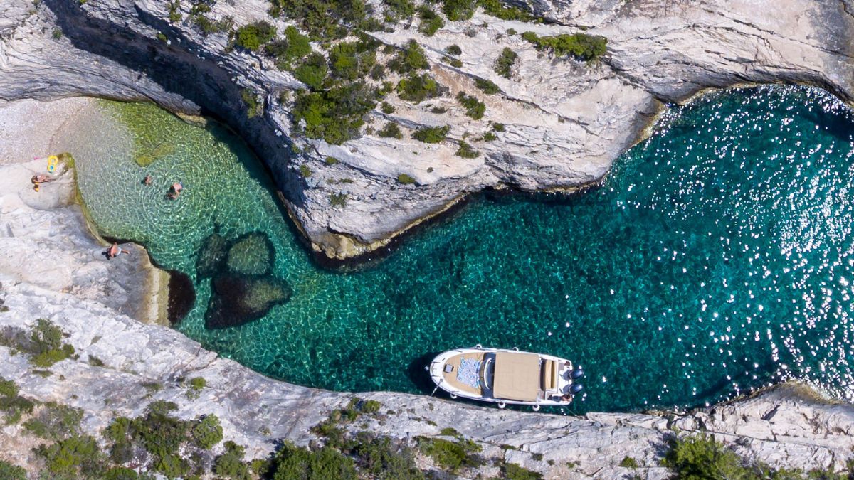 Small tender boat anchored in a turquoise cove on the Croatian coast - perfect for those seeking great beach vacations in August