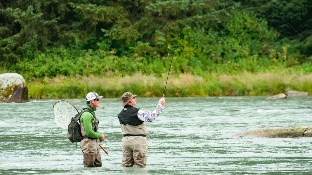 Two men fly-fishing in a river in Alaska