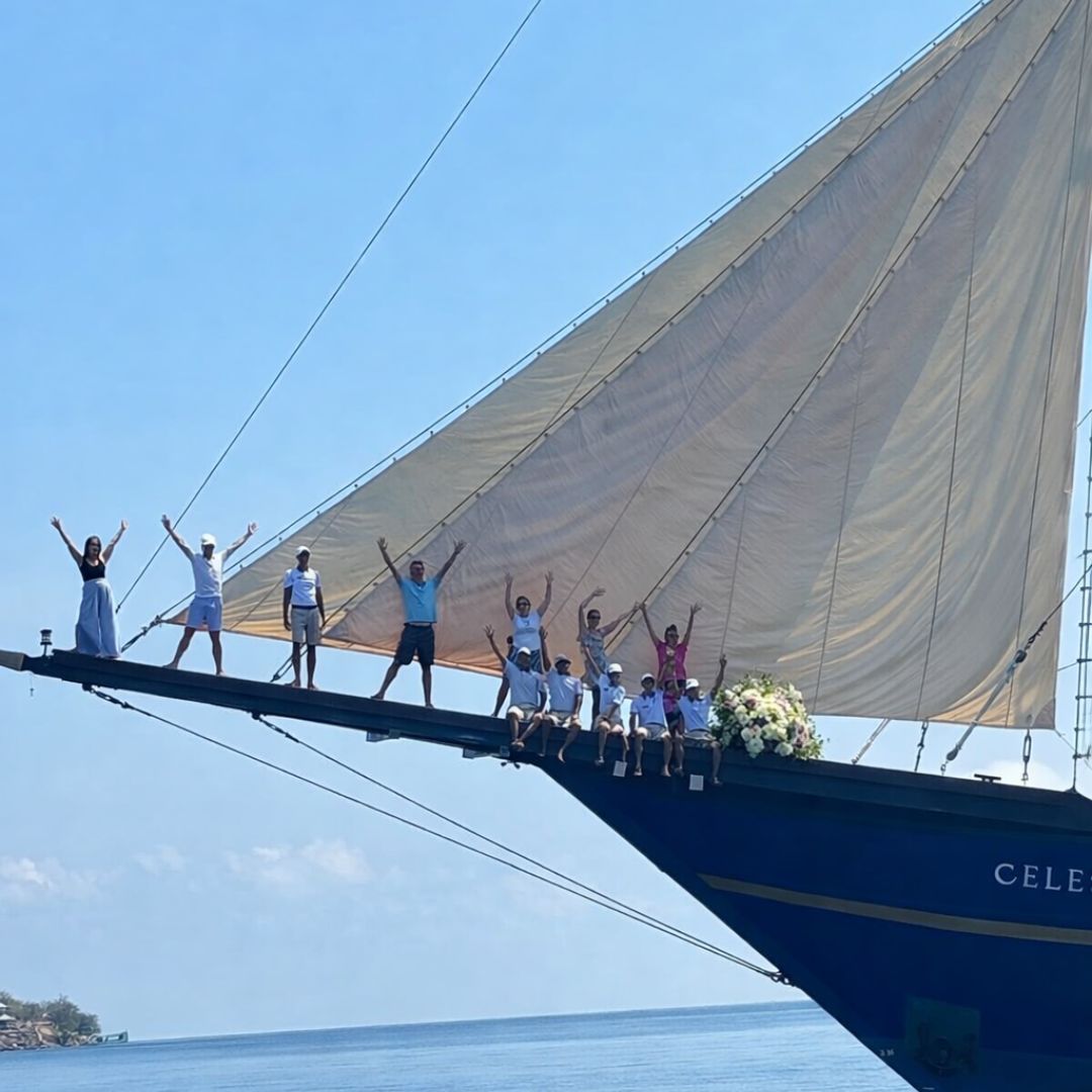 Wedding party celebrating on the bow of a private charter yacht at sea, luxury yacht wedding